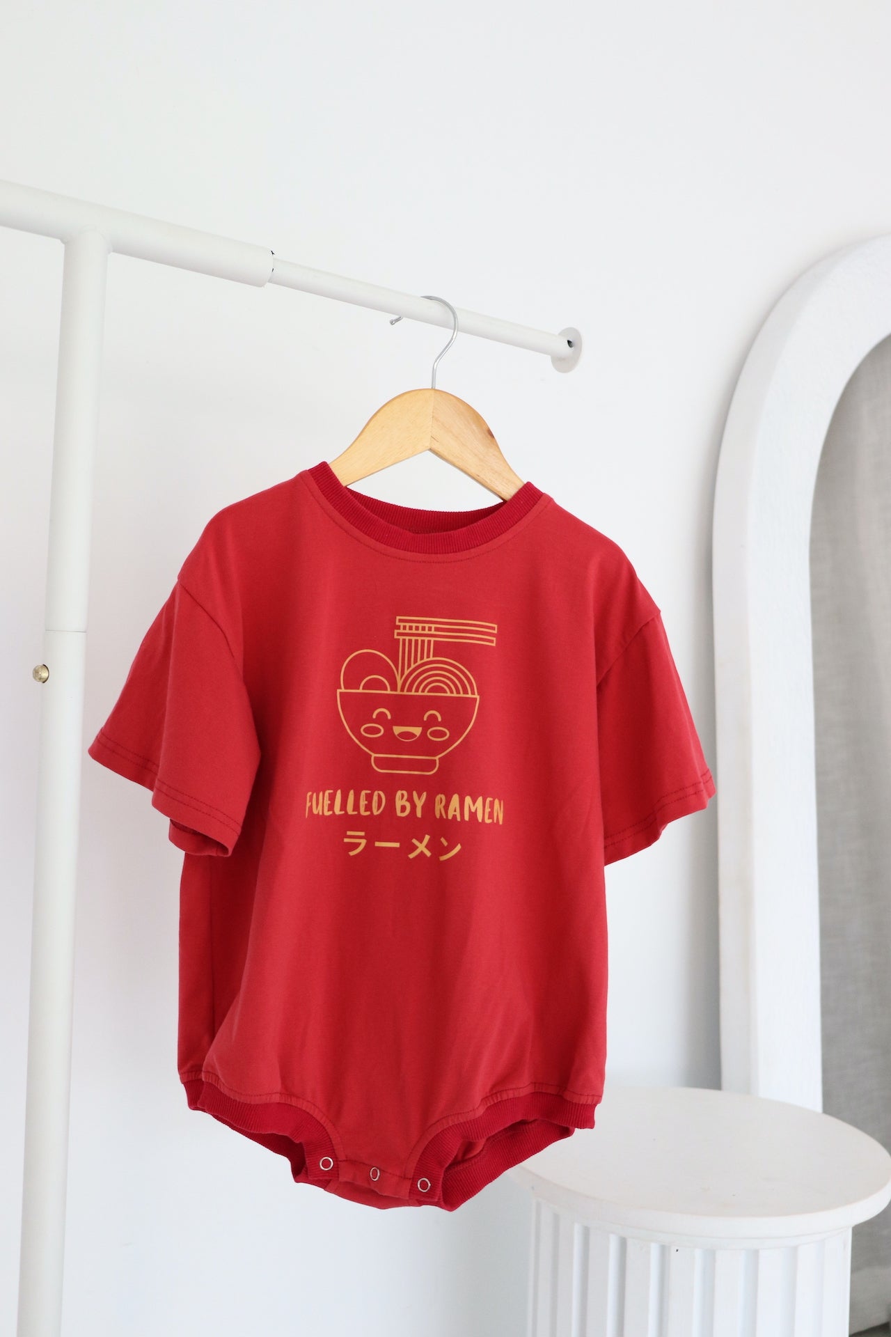 Hanging oversized red romper with an orange ramen bowl logo with 'Fuelled by ramen' writing